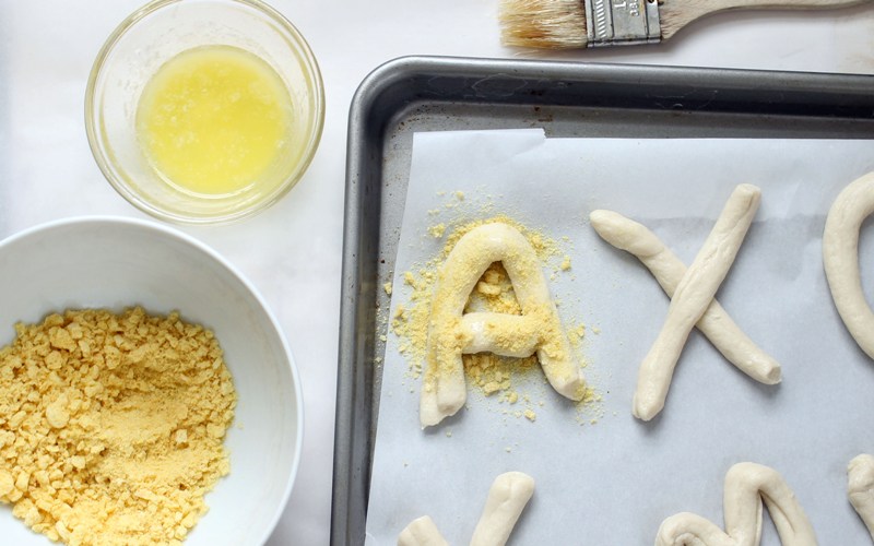 Brush letters with melted butter and sprinkle crushed Kix on top