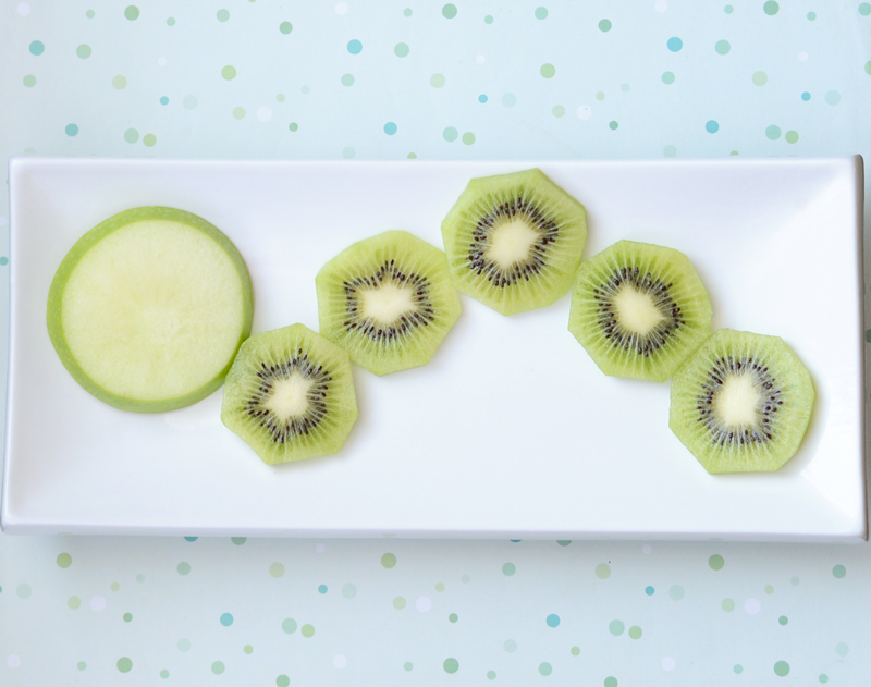 position a slice of apple for the head and kiwi slices for the body