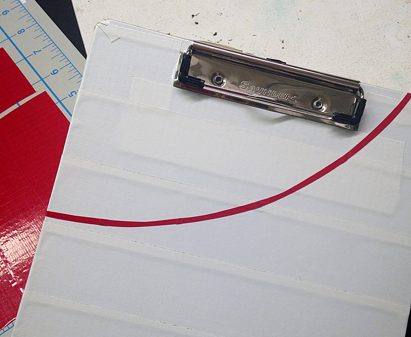 add the curved red tape to the white clipboard